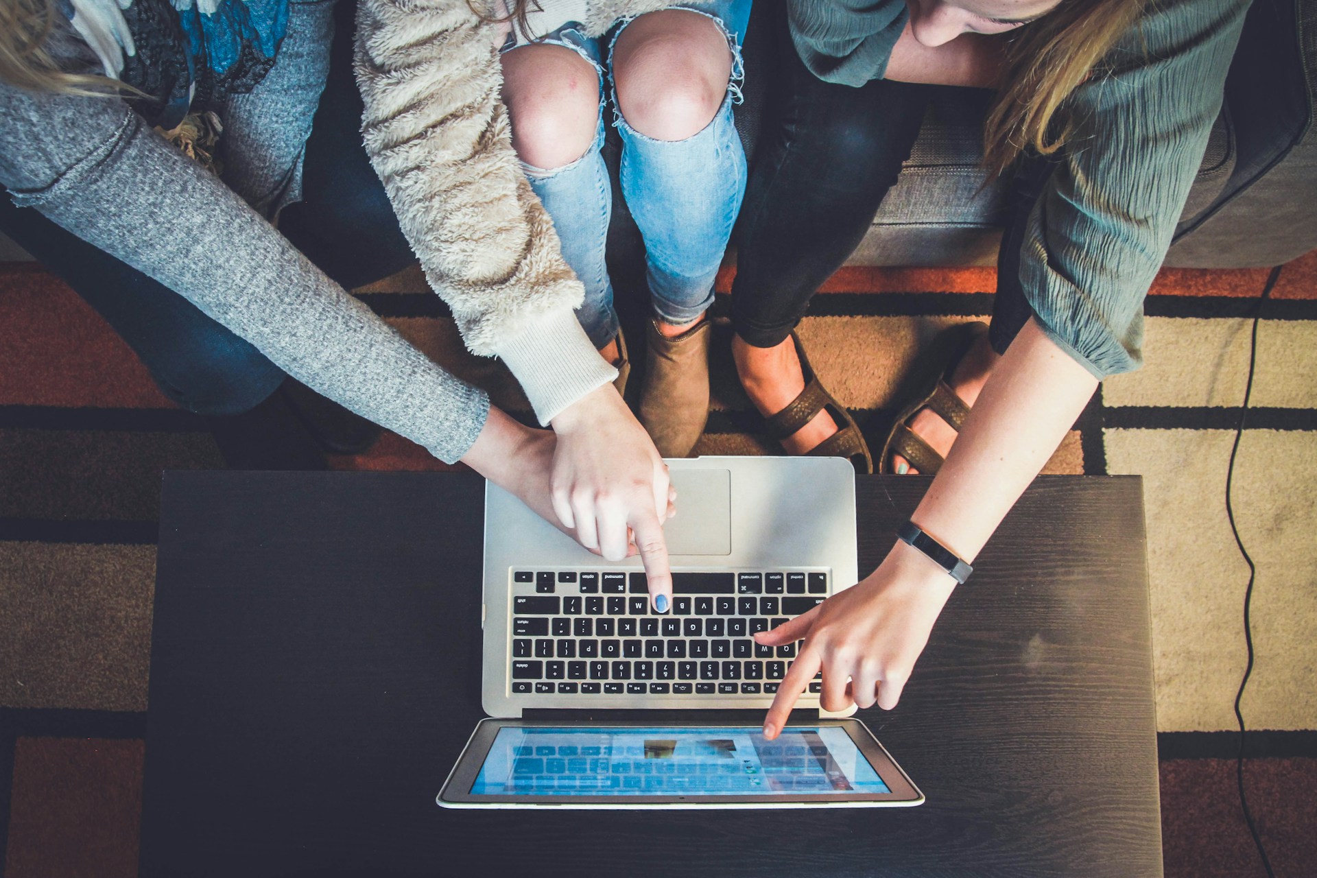 Three woman pointing to a screen on a Macbook computer